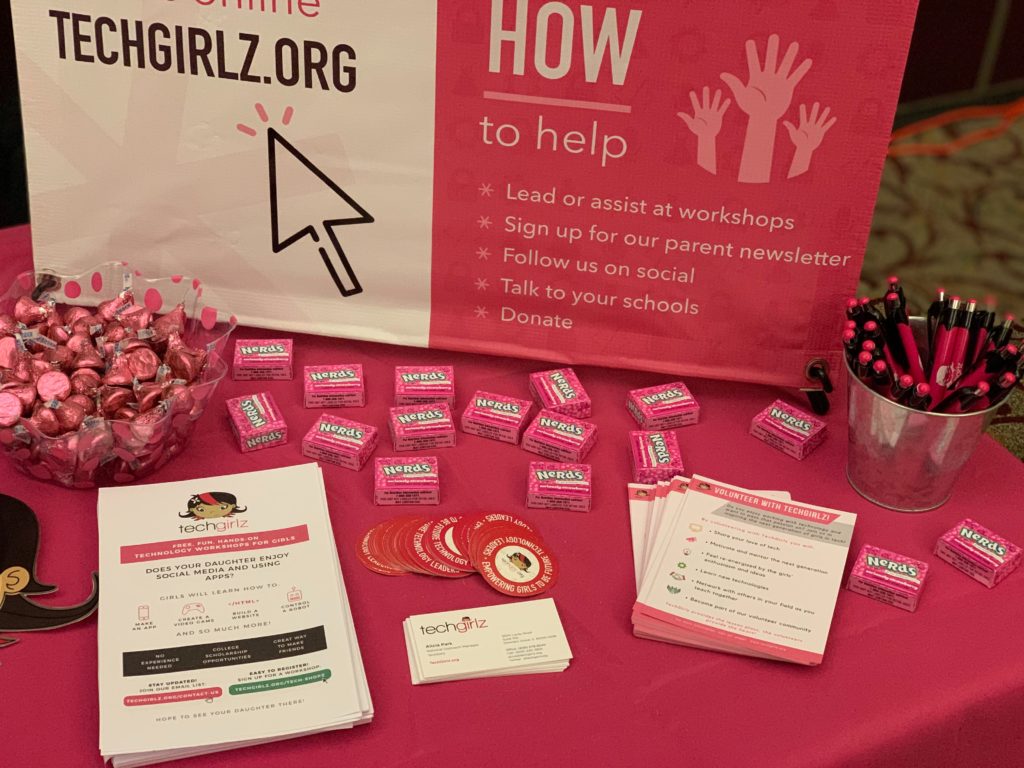 Table with pink TechGirlz stickers, pens, and flyers