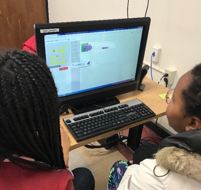 Two girls share a desktop computer to use Scratch