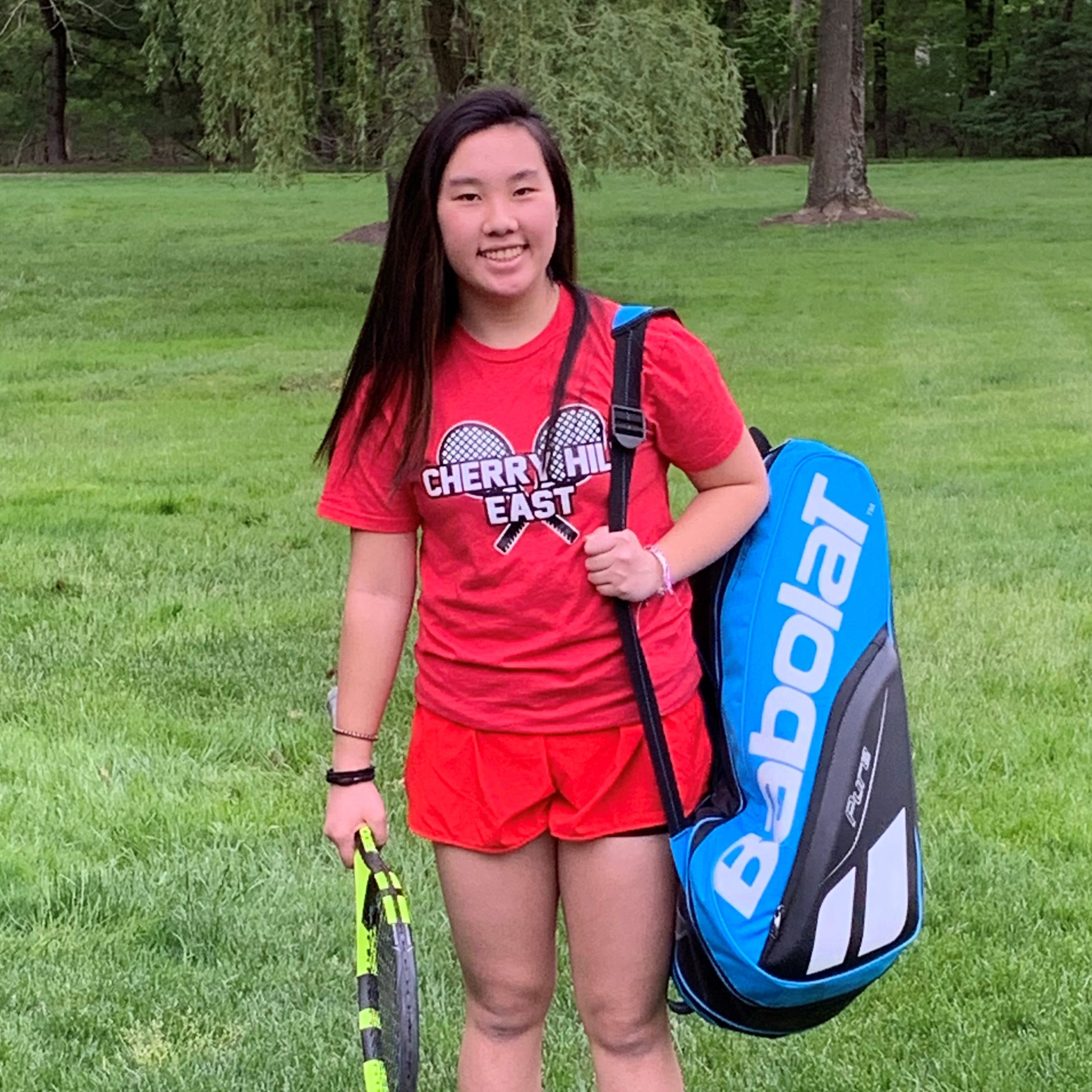 Julia smiling while holding lacrosse equipment